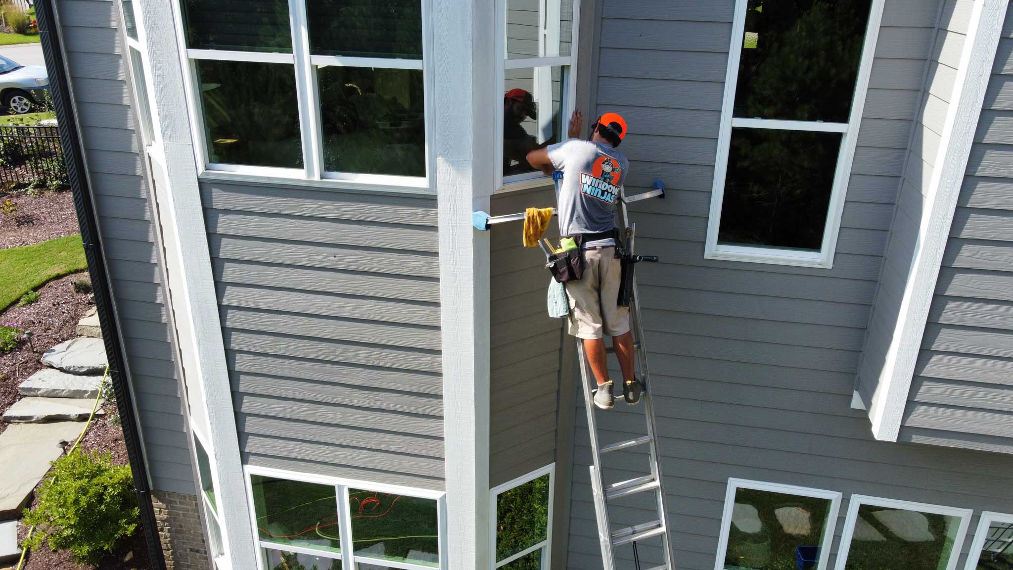 A Window Ninjas Nashville technician cleaning high windows - contact us to learn more about our glass cleaning services!